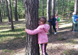 dzieci w lesie przytulają się do drzewa